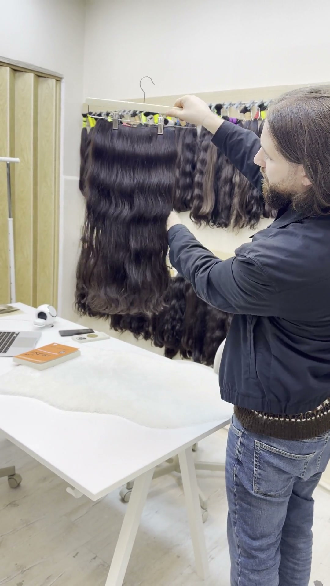 Hair specialist lifting a dark weft beside extension samples.